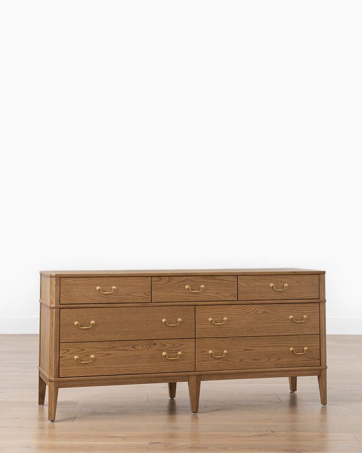 a wooden dresser sitting on top of a hard wood floor next to a white wall