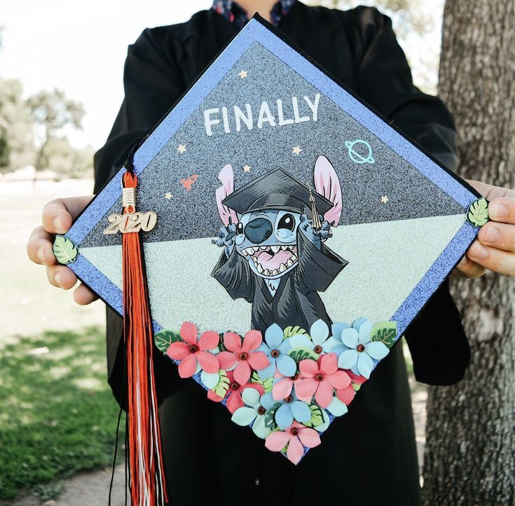 a person holding up a graduation cap with an animal on it