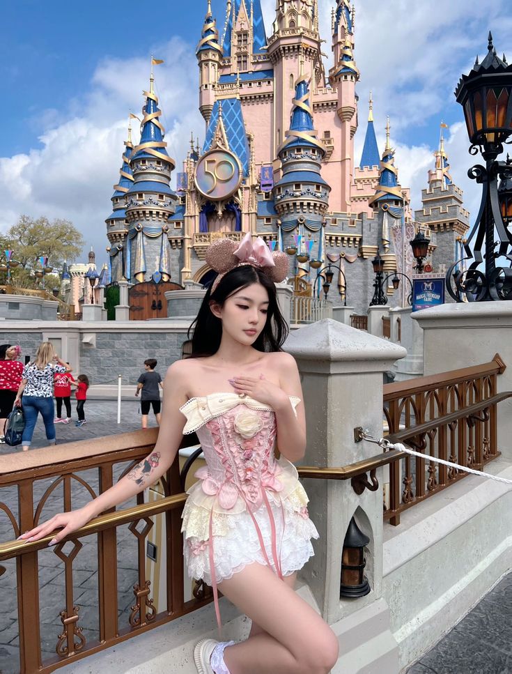 a woman in a corset poses for the camera near a castle at disneyland