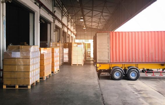 a large yellow truck parked in front of a building with lots of boxes on the ground