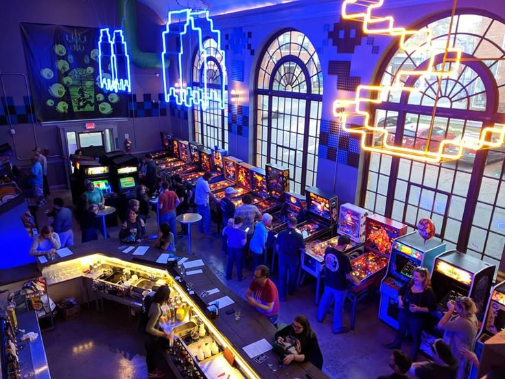 a group of people playing video games in a room with neon lights on the walls