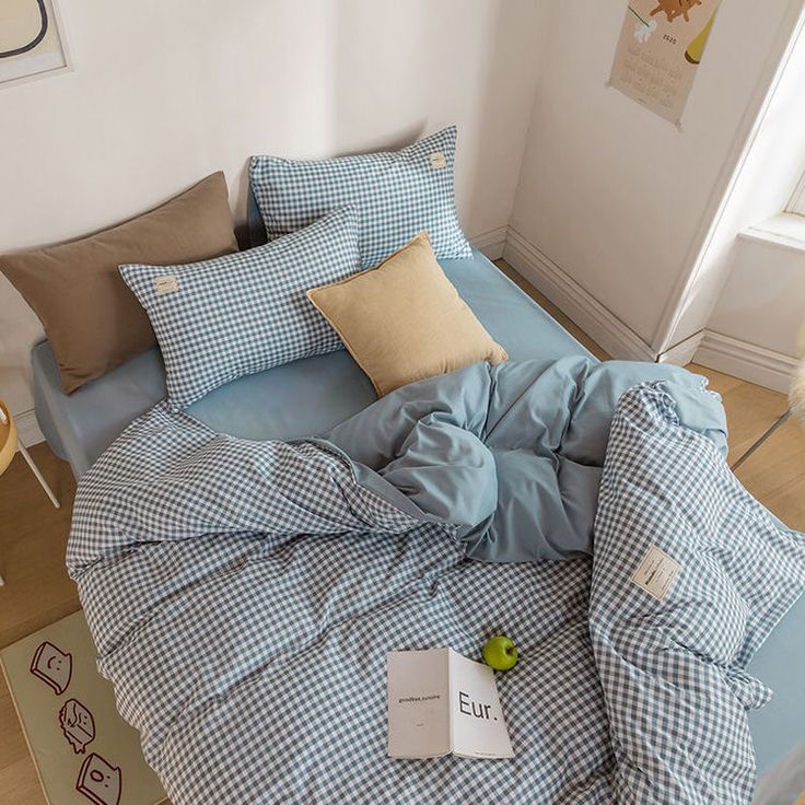 an unmade bed with blue and white checkered comforter, pillows and pillowcases