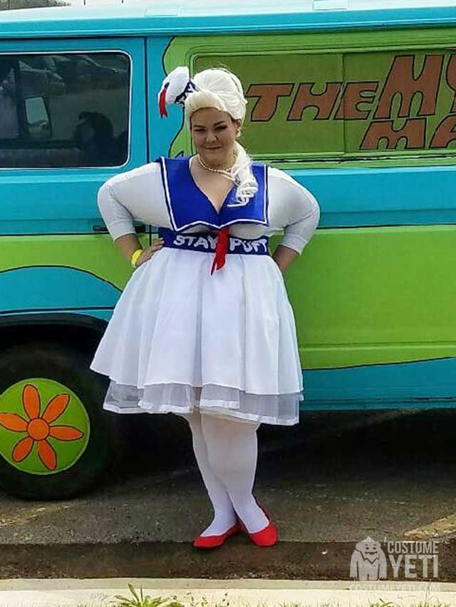 a woman standing in front of a green and blue food truck with her hands on her hips