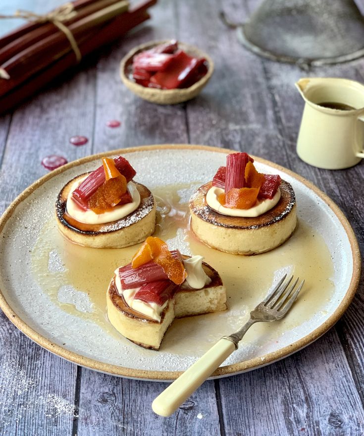 three small pastries on a plate with a fork and cup of coffee in the background