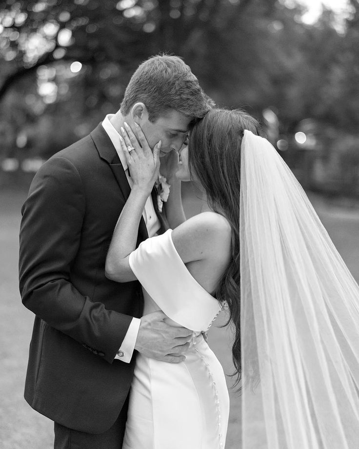 a bride and groom kissing in the park