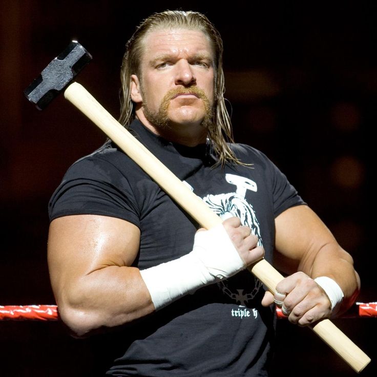 a man with a large hammer in his hand holding a baseball bat and wearing a black t - shirt