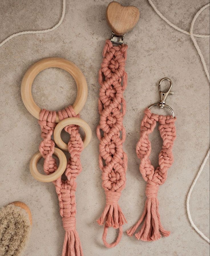 two wooden rings and some pink yarn on a white surface with a wood bead keychain