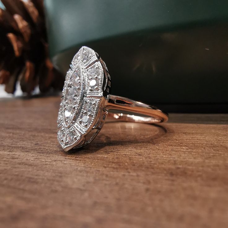 a diamond ring sitting on top of a wooden table next to a pinecone