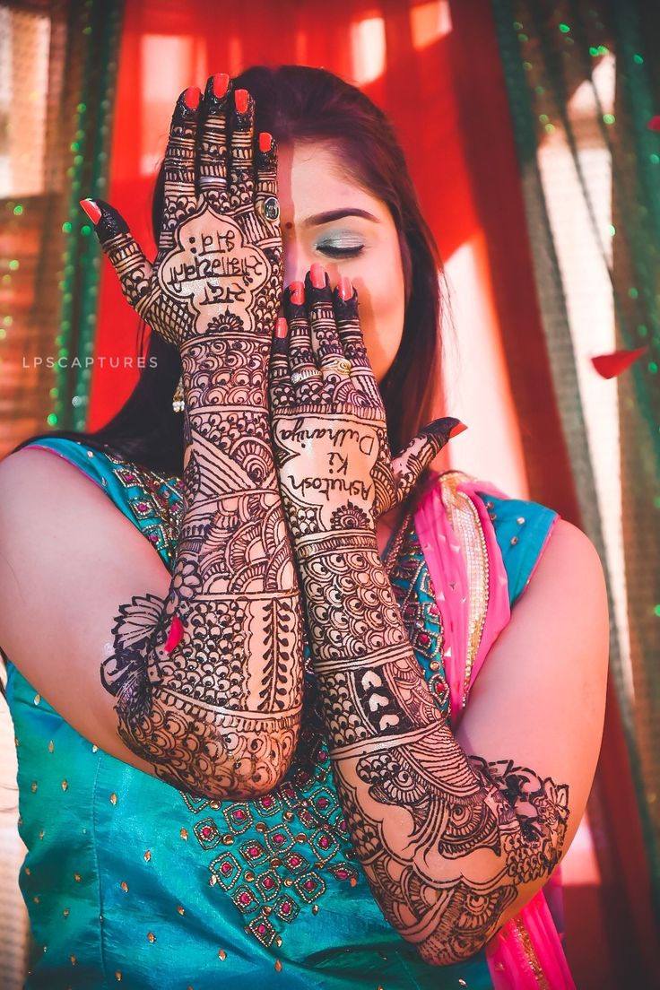 a woman holding her hands up to her face with henna tattoos on it's arms