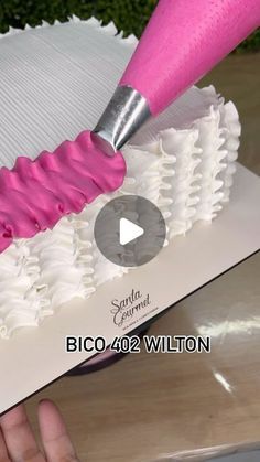 a person is using a pink and white brush to decorate a cake