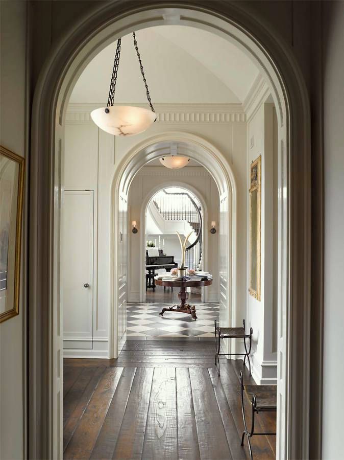 an archway leading to a living room and dining room area with wood flooring, white walls and wooden floors