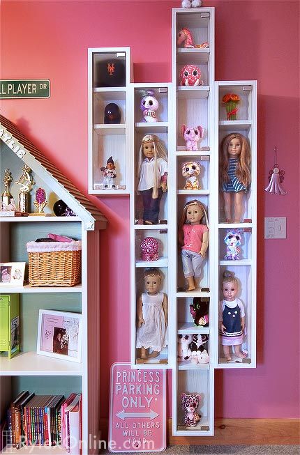 there is a doll house with many dolls in it and shelves on the wall above