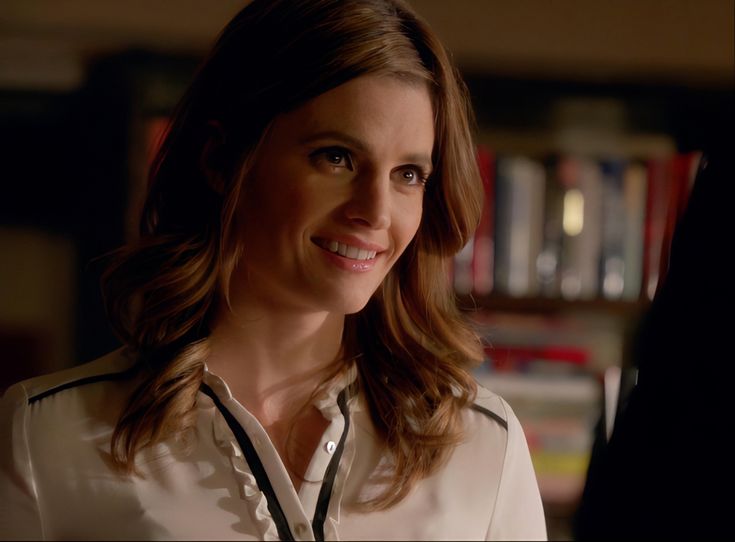 a woman standing in front of a bookshelf with a smile on her face