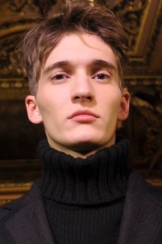 a young man in a black turtle neck sweater looking at the camera with an intense look on his face