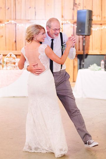 a bride and groom dance together at their wedding reception in front of a wooden wall