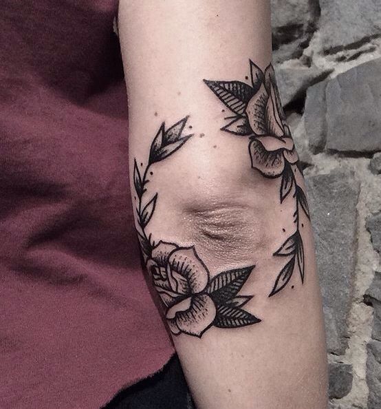 a woman's arm with flowers and leaves tattooed on the left side of her arm