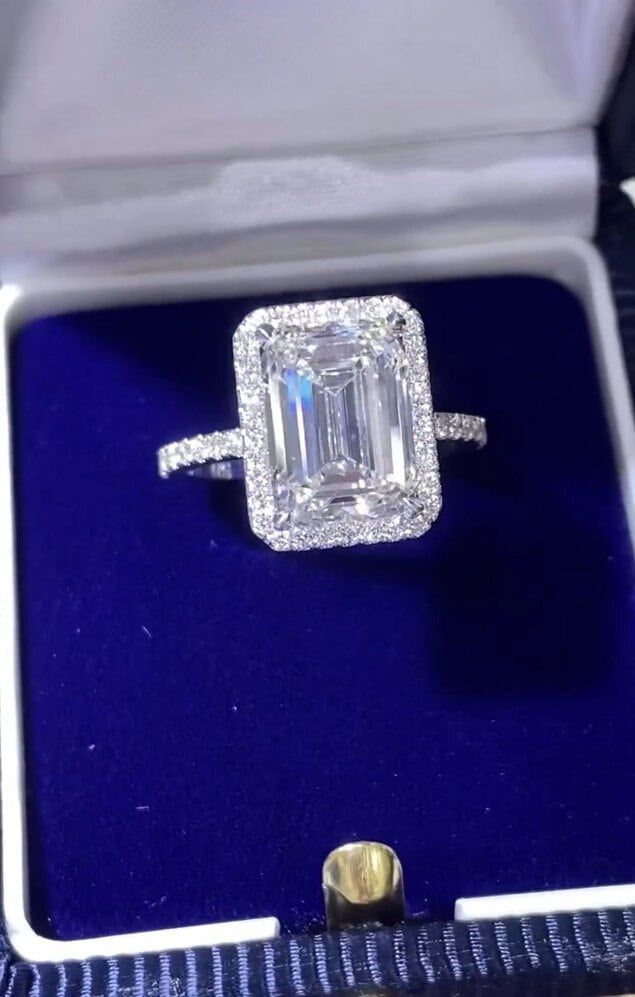 an emerald cut diamond ring in a blue velvet box