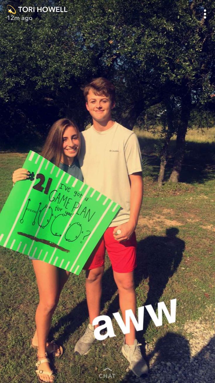 two people standing in the grass holding a green sign that says aww on it