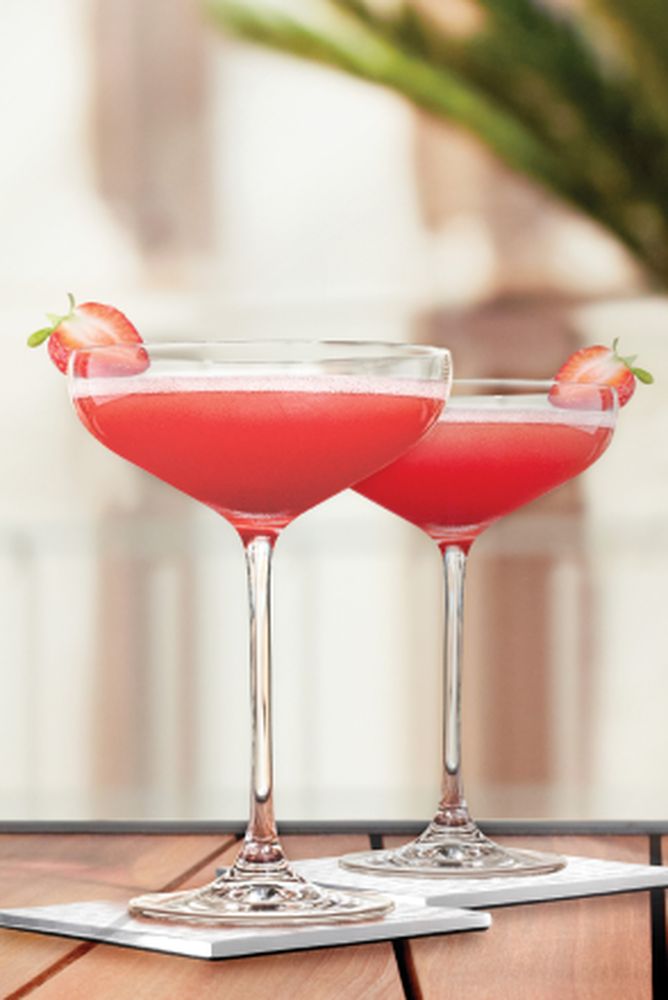 two glasses filled with red liquid on top of a wooden table