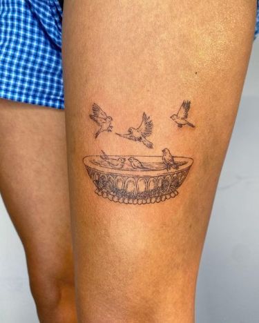 a woman's leg with a tattoo on it that has birds flying over a bathtub