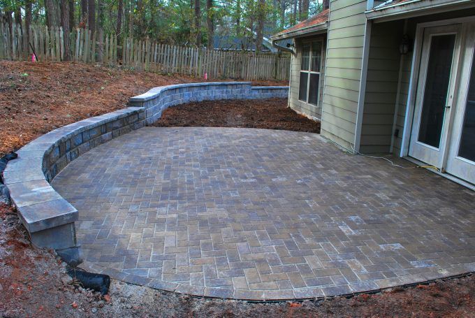 a brick patio with steps leading up to the back door and an outdoor living area