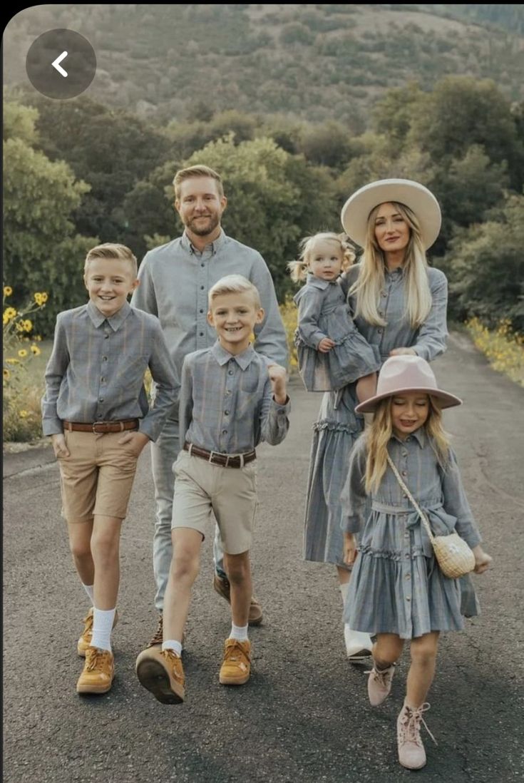 a family is walking down the road with two children and one man wearing a hat