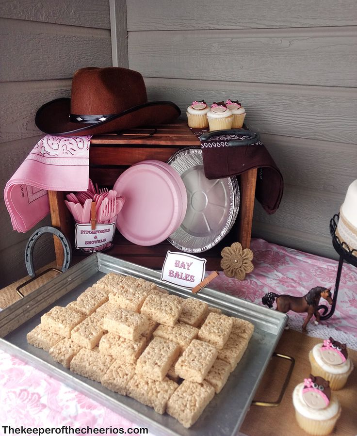 a table topped with lots of cupcakes next to a cake and other items