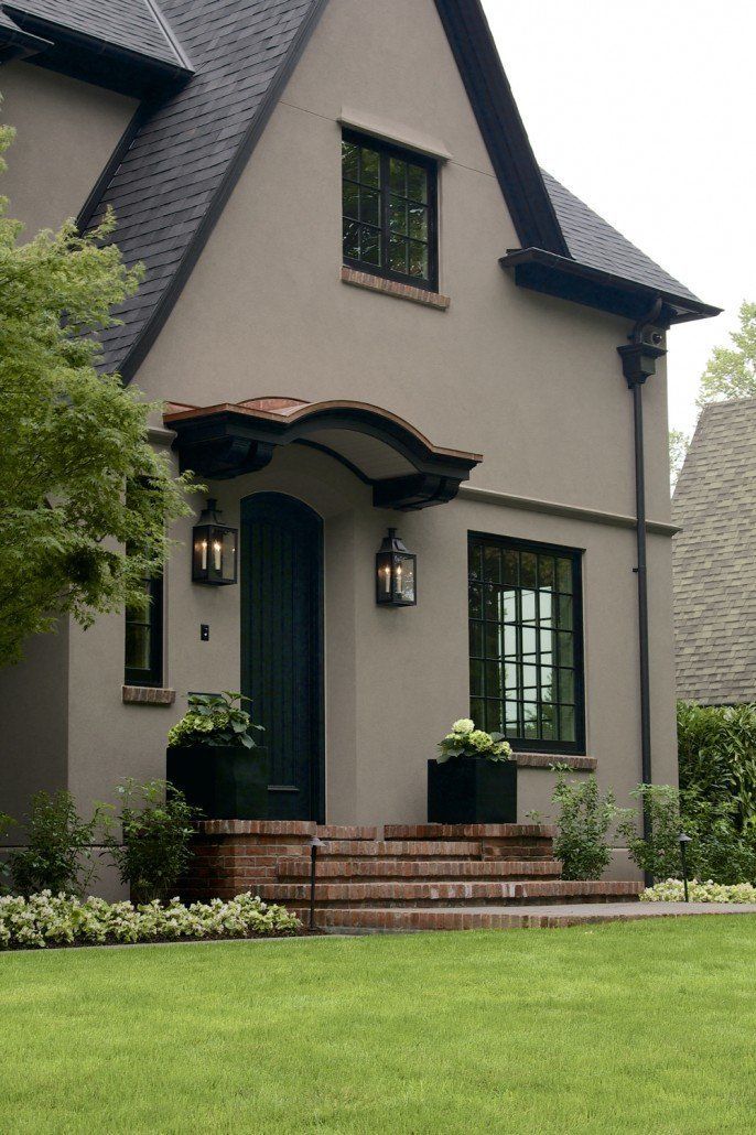 a gray house with black shutters and green doors on the front steps is shown