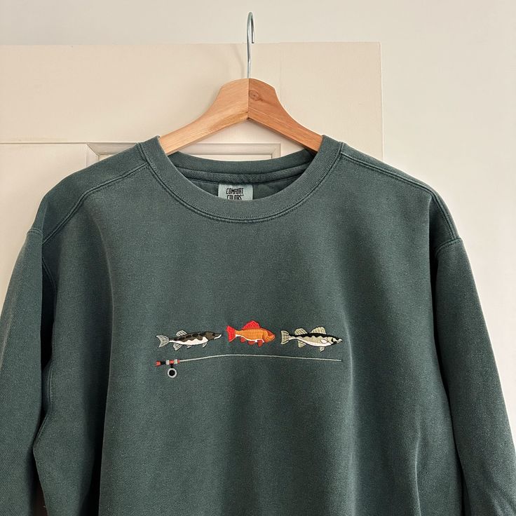 Embroidered crew neck | Comfort Colors Sizes are relaxed unisex size. Material: 80% cotton and 20% polyester Men’s Embroidered Sweatshirt, Embroidery Designs Shirts, Sweatshirt Embroidery Ideas, Fish Sweater, Xmas Vibes, Trendy Sweatshirts, Outdoorsy Style, Embroidery Hoop Wall Art, Fishing Gift