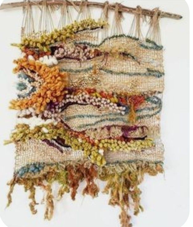 a piece of art made out of fabric and beads hanging from a wooden frame on a wall