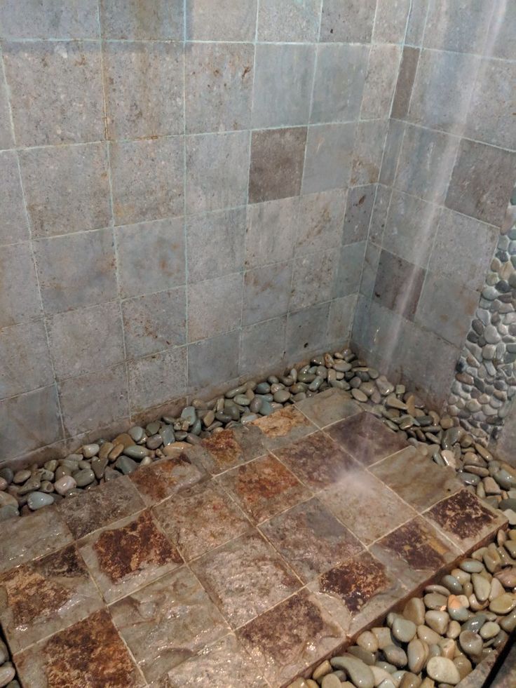 a stone shower with rocks on the floor and in between it is a tiled wall