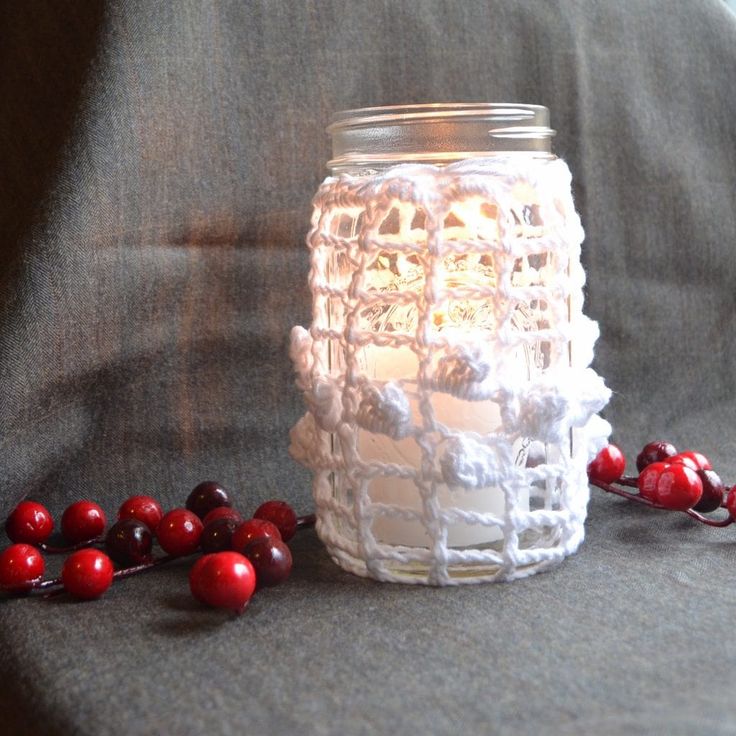 a glass jar filled with cranberries on top of a gray cloth covered table