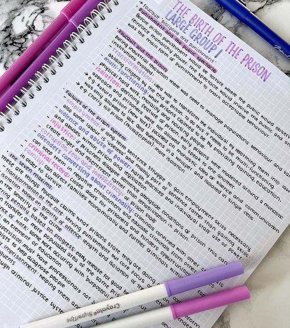 three pink and purple pens sitting on top of an open notebook next to another pen