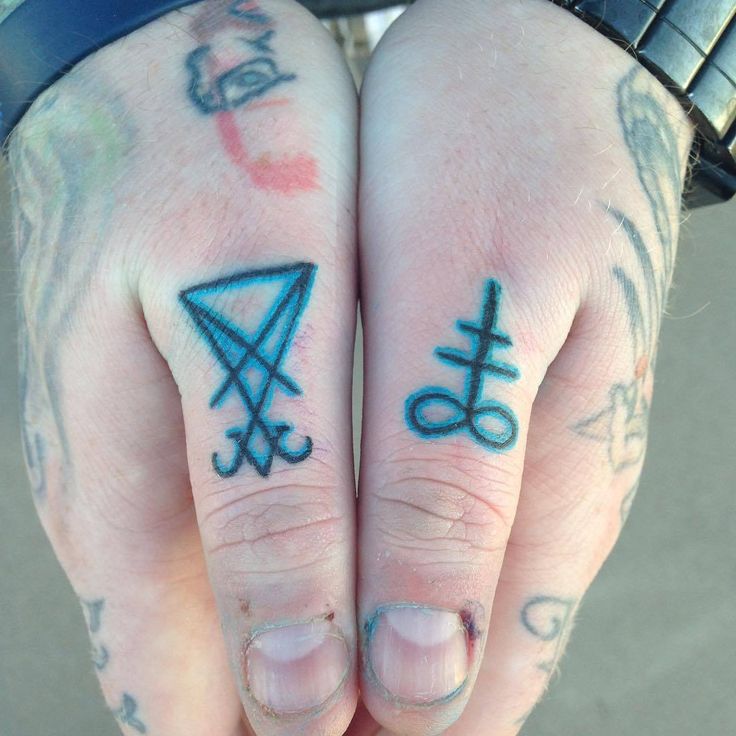 two people with tattoos on their hands holding onto one another's fingers and the other hand has an upside down symbol