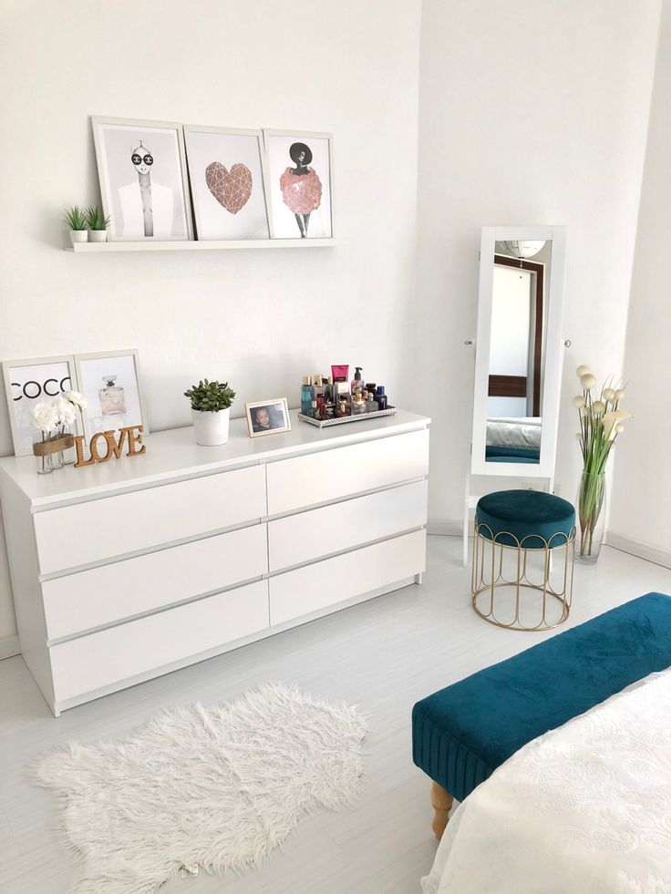 a bedroom with white walls and blue accents on the dressers, mirror and stool