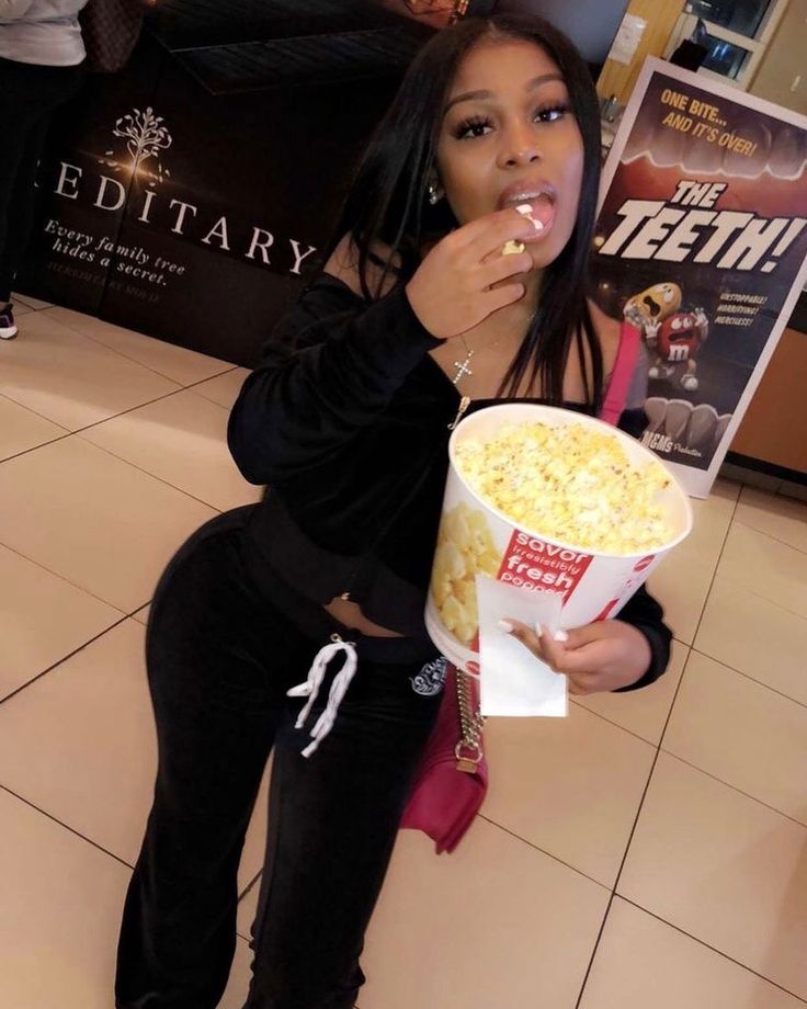 a woman sitting on the floor eating popcorn