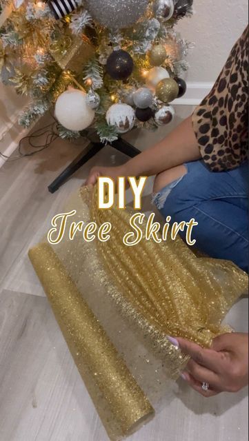 a woman sitting on the floor next to a christmas tree with gold sequins