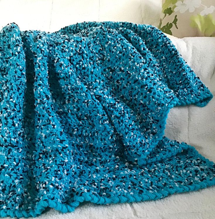 a blue crocheted blanket sitting on top of a white couch