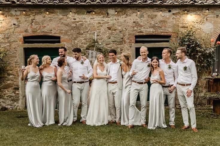 a group of people standing next to each other in front of a stone building with windows