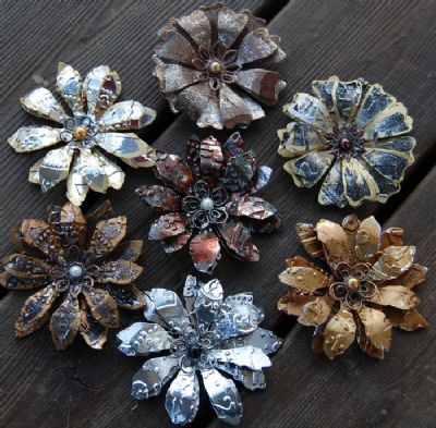 four different types of flower brooches sitting on top of a wooden table