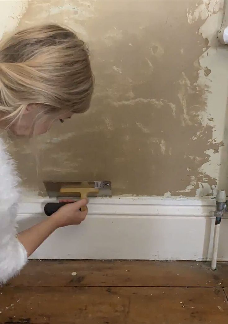 a woman is painting the wall with paint rollers