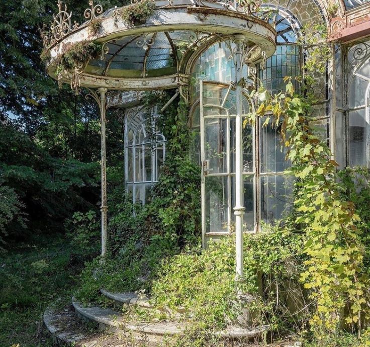 an old gazebo surrounded by vines and ivys in front of a glass house