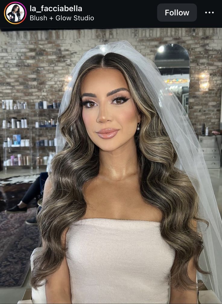 a woman with long hair wearing a bridal veil and looking at the camera in a salon