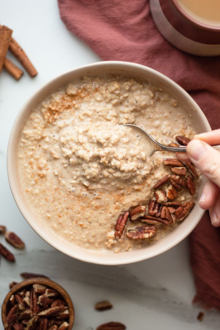 a bowl of oatmeal with pecans and cinnamon sticks on the side