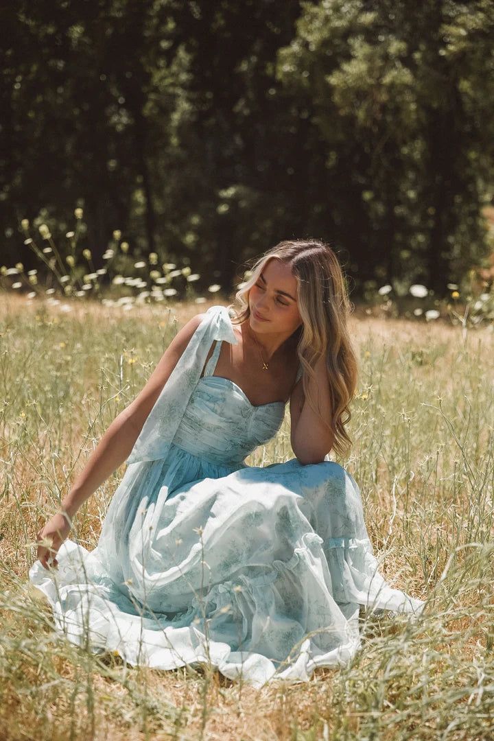 a woman in a blue dress sitting on the ground