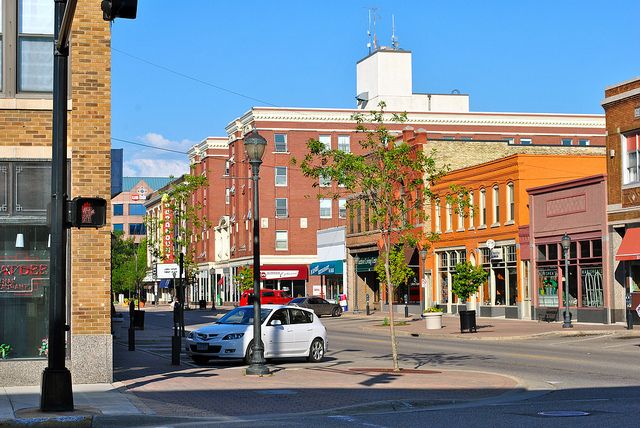 cars are parked on the street in front of shops and businesses near a traffic light