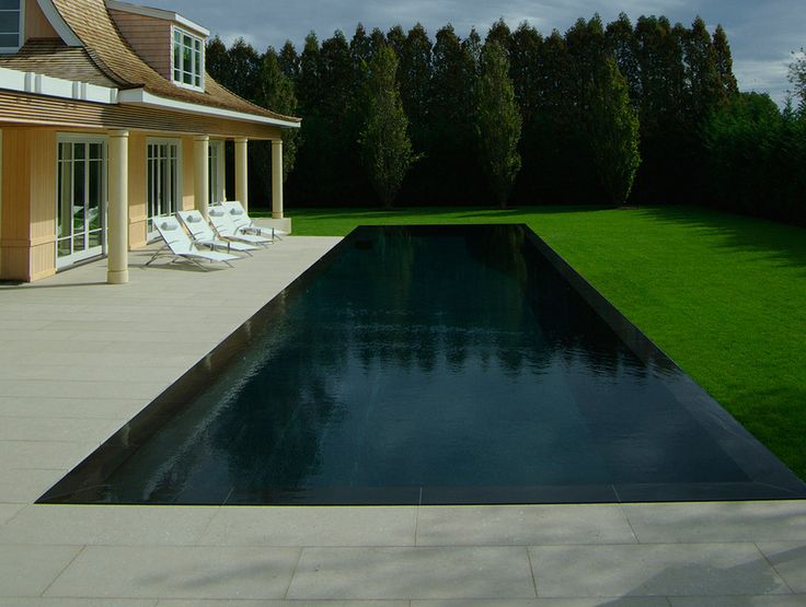 a house with a pool in front of it and grass around the pool area on either side