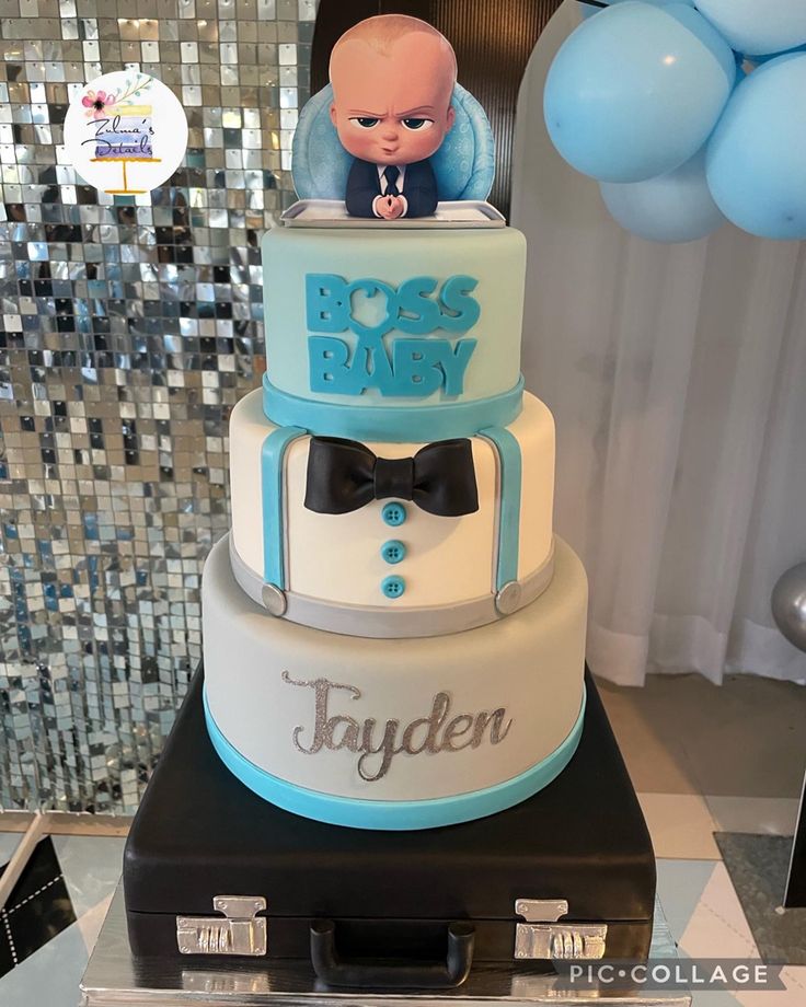 a three tiered cake with an image of a baby on top and blue balloons in the background