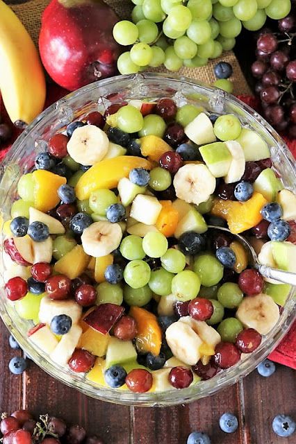 a glass bowl filled with fruit next to grapes and bananas