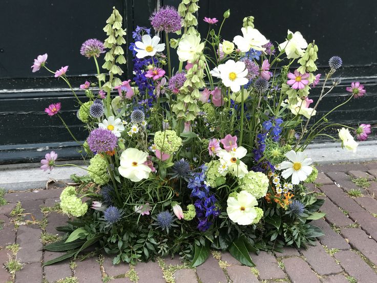 a bunch of flowers that are sitting on the ground in front of a black door